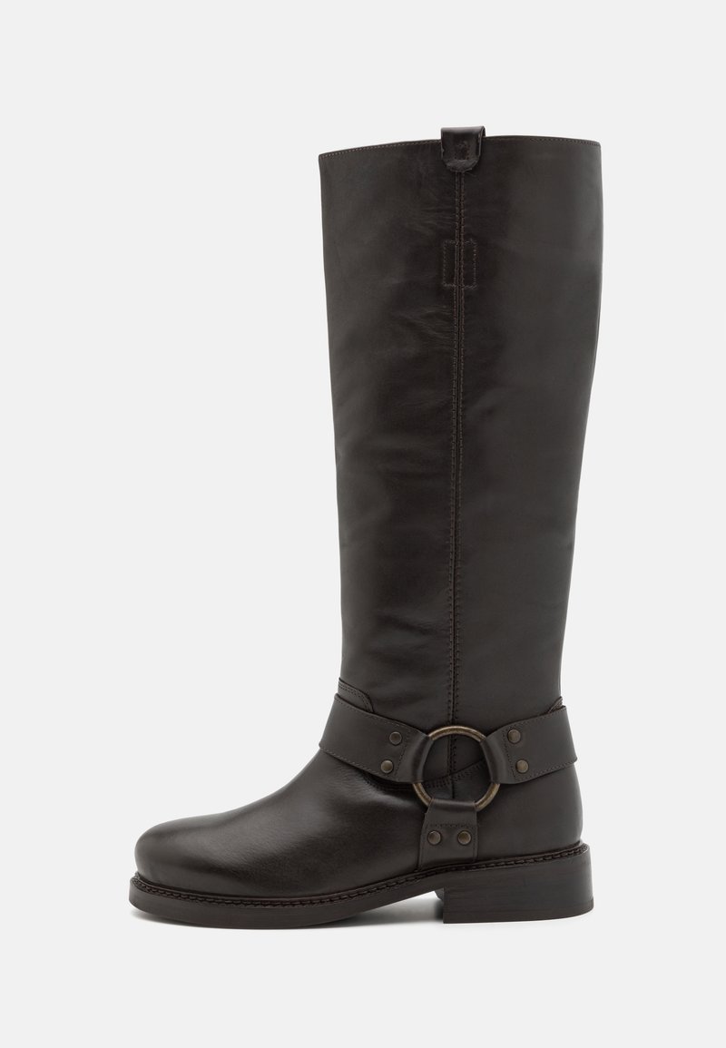 Botte en cuir noire montante jusqu'au genou avec bout rond, talon bas et bride décorative avec anneau métallique autour de la cheville.