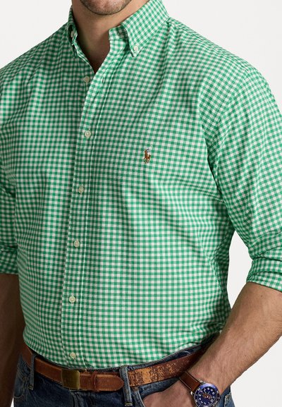 Chemise à carreaux vichy verts et blancs avec un col boutonné et un petit logo brodé. Présente des manches ajustées et une texture en coton doux.