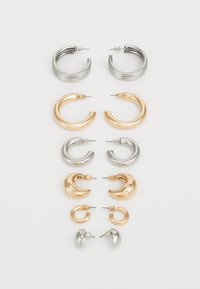 Set med åtta metallörhängen i silver- och guldtoner. Inkluderar olika stilar av hoops, texturer och ytor, ordnade efter storlek.