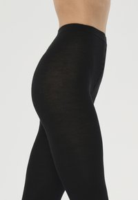 Svarta leggings med en slät textur och elastisk midja, figurnära design och utan synliga mönster eller hårdvarudetaljer.