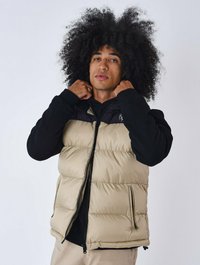 Gilet imbottito beige e nero, con chiusura zip frontale, tasche laterali e texture trapuntata. Il design include un colletto nero.