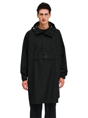 Mężczyzna w czarnej, luźnej, za dużej przeciwdeszczowej kurtce z kapturem, przednią kieszenią i sznurkami, stojący na białym tle.