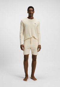 Beige loungewear set met een lange mouw top met ronde halslijn en shorts met een verstelbare trekkoord taille, gemaakt van gestructureerde stof.