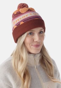 Knit beanie in orange, cream, and burgundy with a pom-pom on top. Features striped pattern and "Smartwool" text in bold letters. Ribbed edge.