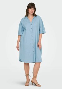 Robe chemise en lin bleu clair avec des manches courtes, bouton devant et une silhouette décontractée. Présente un col et des détails de manches retroussées.