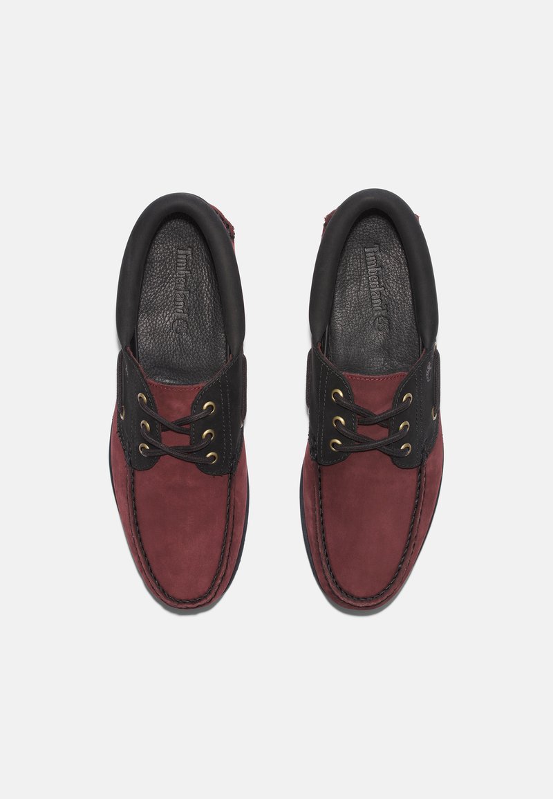 Zapatos de ante rojo con detalles en cuero negro, diseño con cordones, ojales dorados, cuello acolchado y plantilla texturizada. Estilo clásico y casual.