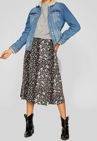 Jeansowa kurtka z futrzanym kołnierzem, szary sweter i czarna spódnica midi w kwiaty, połączone z czarnymi botkami za kostkę dla uzyskania warstwowego wyglądu.