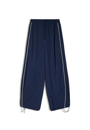 Pantalon bleu marine à jambes larges avec bandes latérales blanches, taille élastique, cordon de serrage et ourlets ajustables, à plat sur fond blanc.