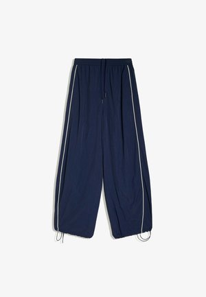 Pantalon bleu marine à jambes larges avec bandes latérales blanches, taille élastique, cordon de serrage et ourlets ajustables, à plat sur fond blanc.