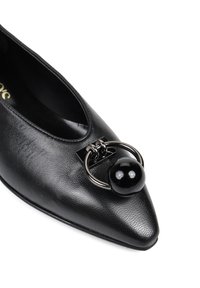 Czarny skórzany but z szpiczastym noskiem, wyposażony w okrągły czarny element dekoracyjny oraz metalowe okucia z przodu. Teksturowane wykończenie wierzchu.