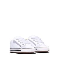 Paire de petites baskets en toile blanche pour bébé avec des lacets blancs et des semelles en caoutchouc texturées sur un fond blanc.