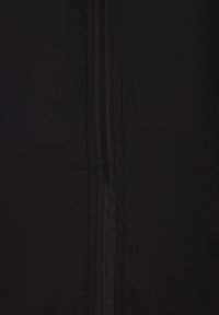 Black fabric with a smooth texture features a central zipper. The design is simple, lacking patterns or additional accents.