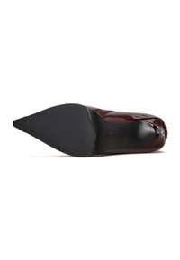 Chaussure à talon haut en cuir vernis bordeaux avec un bout pointu et une semelle en caoutchouc noir lisse, présentant un talon arrondi et un détail de marque discret.