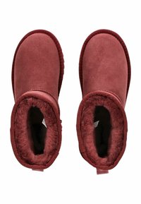 Stivale alla caviglia bordeaux in morbido suede con un interno sfoderato e dettagli cuciti, caratterizzato da una punta tonda e un’impugnatura sul retro.