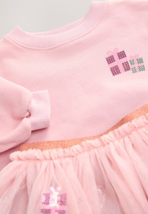 Roze sweatshirt met geribde halslijn, voorzien van een tule rok. Geborduurde cadeaupeltjes in roze en groen met pailletten aan de onderkant.