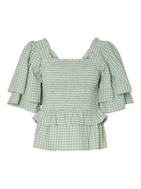 Blusa a quadri verde e bianca con maniche corte e arricciate, corpino smockato e orlo peplum svasato. Accentuata da un collo a onde.