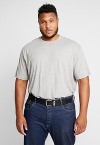 T-shirt gris à manches courtes avec un col rond, porté avec un jean en denim bleu et une ceinture noire avec une boucle en argent.