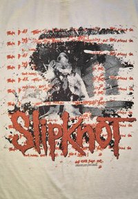 Biały T-shirt z czarno-czerwonym nadrukiem graficznym. Zawiera tekst oraz ilustrację postaci w masce, z efektem rozprysków i wyraźnymi literami.