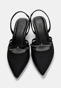 Svarta slingback-klackar med spetsiga tår, satsbyggd yta och en dekorativ rosett prydd med små rhinstenar.