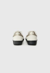 Sport shoes with a white leather upper, gray accents, and black rubber soles. Features prominent "NIKE" branding on the heel.