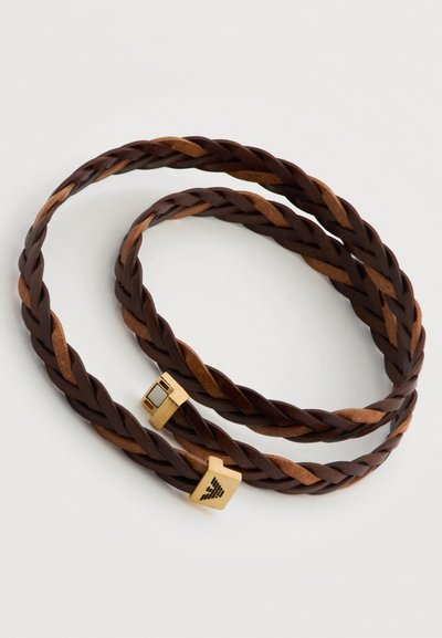 Πλεγμένο βραχιόλι από δέρμα σκούρου και ανοιχτού καφέ χρώματος με κούμπωμα σε χρυσό χρώμα που φέρει μαύρη χαραγμένη λογότυπο, τυλιγμένο επίπεδα πάνω σε λευκό φόντο.