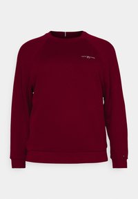Bordeauxrode sweatshirt met raglanmouwen, ronde hals en geribbelde manchetten. Voorzien van een subtiel wit logo op de borst. Zachte textuur.