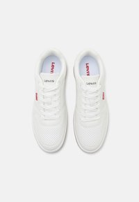 Weiße Sneakers mit Leder- und Perforierungsdesign. Ausgestattet mit Baumwollschnürsenkeln, gepolstertem Kragen und einem roten Levi's-Tag an der Seite.
