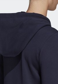 Sweatshirt bleu marine avec une texture douce, dotée d'une grande capuche et d'un design simple ; couture visible le long des épaules et du cou.