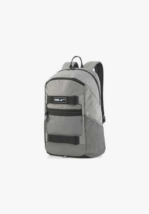 Szary plecak Puma z wieloma komorami zapinanymi na zamek błyskawiczny, czarnymi paskami i siateczkową boczną kieszenią, pokazany na białym tle.