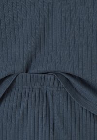 Close-up of dark blue ribbed fabric with elastic waistband and visible stitching detail.