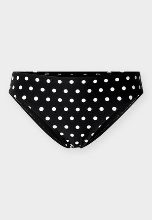 Slip da bikini nero con pois bianchi uniformemente distribuiti, posizionato disteso su uno sfondo grigio chiaro uniforme.