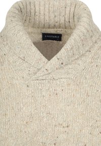 Gebreide trui in crèmekleur met een hoge kraag, voorzien van een gestructureerd patroon en kleurvlekjes door het hele kledingstuk. Merklap zichtbaar.