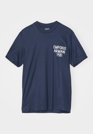 T-shirt in cotone blu navy con scollatura rotonda, maniche corte e testo stampato bianco "EMPORIO ARMANI 1981" sul lato sinistro del petto.