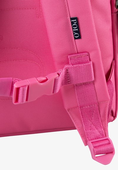 Ροζ σακίδιο πλάτης με υφή υφάσματος, ρυθμιζόμενο λουρί με πλαστικό κούμπωμα και ετικέτα λογότυπου σε ναυτικό μπλε χρώμα.