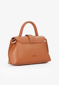 Piccola borsa a mano in pelle color beige con manico superiore, chiusura a patta e logo del brand discreto sul davanti, su sfondo bianco.