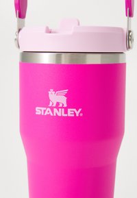 Pink stainless steel tumbler with a matte finish, featuring a silver band at the top and a logo of a winged bear. Includes a pink lid.