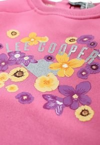 Sweat-shirt rose avec imprimé floral en violet et jaune. "LEE COOPER" est inscrit en lettres argentées sur le devant avec un fond texturé.