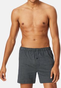 Boxers noirs et blancs rayés pour hommes avec une taille élastique et un détail de bouton à l'avant. Tissu doux avec une coupe ajustée.
