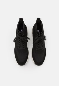 Zapatillas deportivas negras con empeine de punto, diseño con cordones, puntera redonda y suela de contraste con acabado liso.