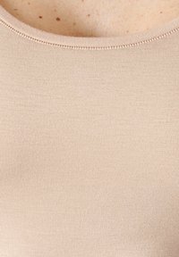 Top beige aderente con texture a coste e scollo rotondo. I dettagli delle cuciture attorno al colletto aggiungono un design sottile.