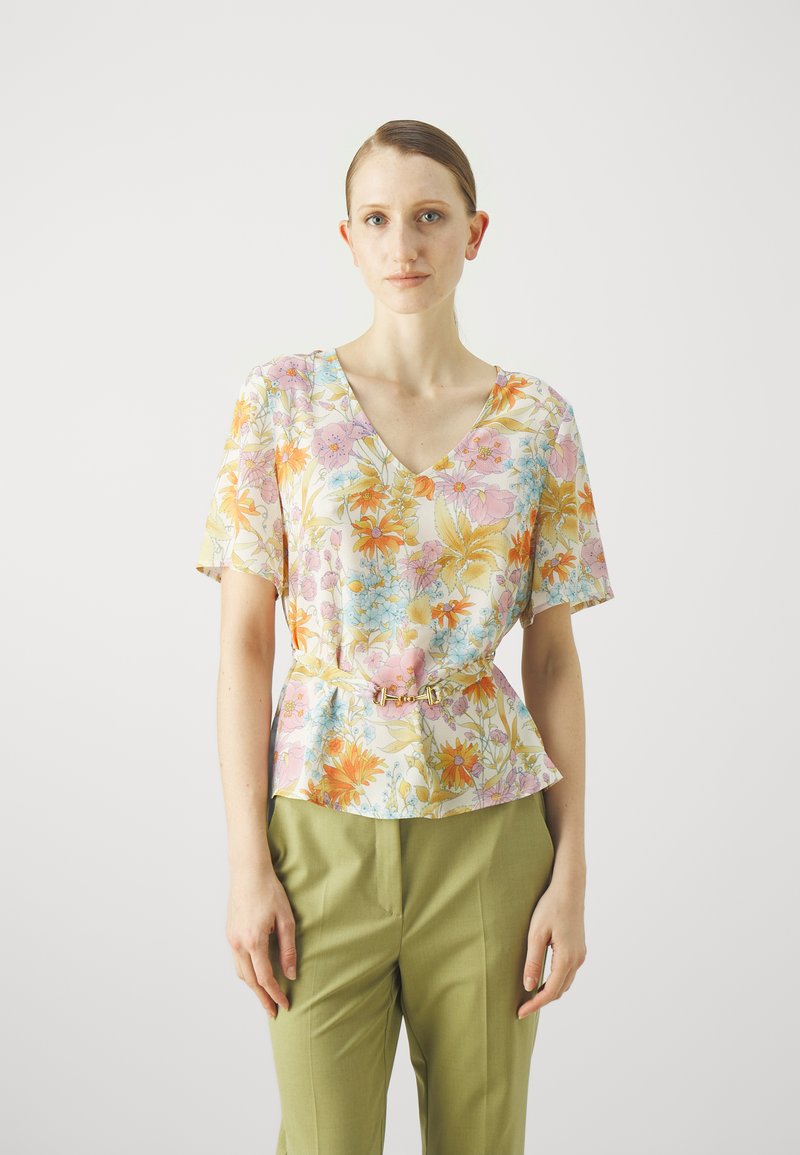 Floral Peplum-Top mit kurzen Ärmeln, ausgestattet mit einem V-Ausschnitt, buntem Muster aus rosa, orange und blauen Blumen sowie einem goldenen Schnallen-Gürtel.