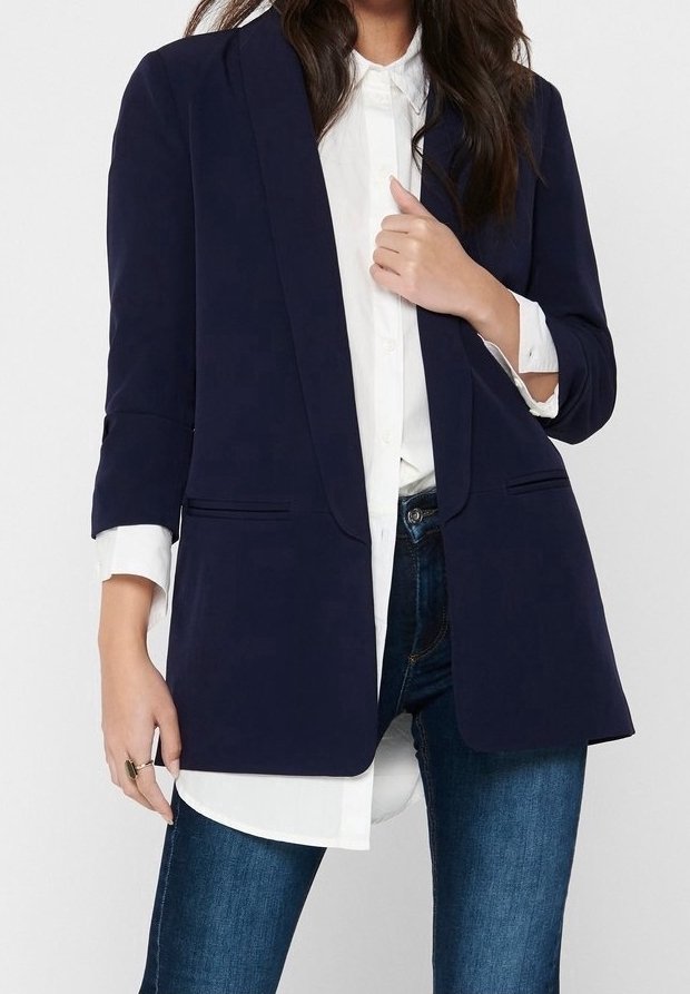 Blazer bleu marine à coupe décontractée, avec des revers crantés et deux poches avant, porté sur une chemise blanche et associé à un jean bleu.