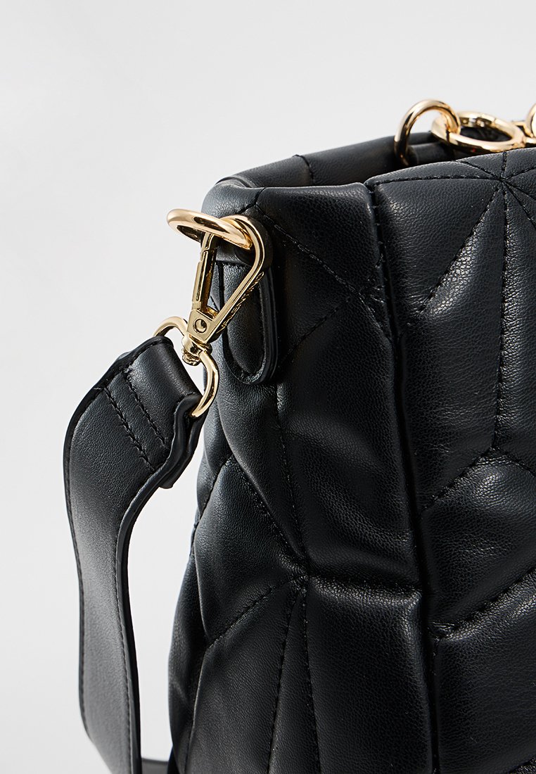 Sac à main en cuir matelassé noir avec une forme structurée, des accents en métal doré et une texture rembourrée. Anse réglable incluse.