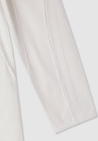 Pantaloni in denim bianco con cuciture laterali sfrangiate, vestibilità slim e taglio dritto. Il tessuto ha una consistenza liscia con dettagli di cucitura visibili.