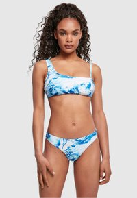 Bikini set u plavo-bijelom mramornom uzorku; gornji dio s jednim naramenicom, donji dio je s niskim strukom i umjerenim pokrićem.