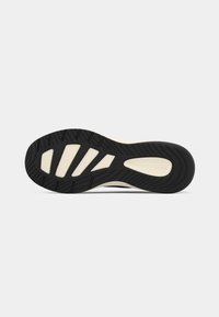 Black rubber outsole with textured tread pattern, featuring a cream-colored midsole. Design includes grooves for traction and flexibility.
