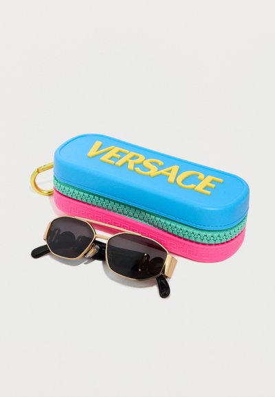 Θήκη γυαλιών ηλίου Versace σε μπλε, πράσινο και ροζ χρώμα με κίτρινο λογότυπο δίπλα σε ορθογώνια γυαλιά ηλίου με μαύρους φακούς και χρυσά πλαίσια.