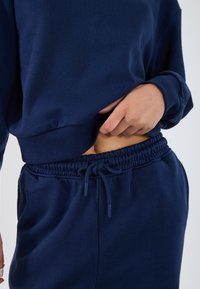 Navy blue sweatshirt with ribbed cuffs and hem, paired with matching jogger pants featuring an elastic waistband and drawstring.