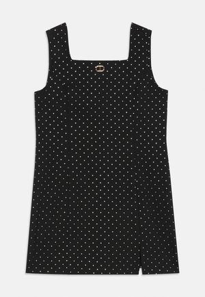 Sort ærmeløs mini kjole med hvide prikker, firkantet halsudskæring, let i front, og lille guldbeslag detaljeret ved brystet.