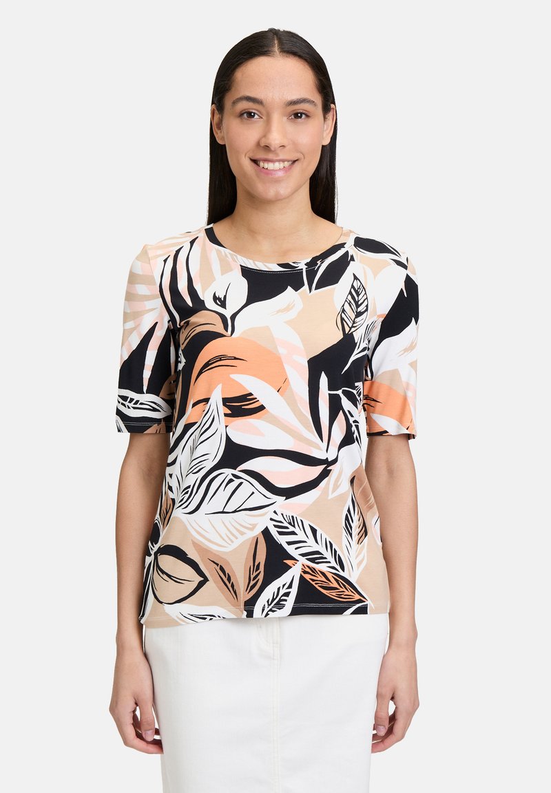 Haut à manches courtes avec un motif de feuilles noir, blanc et pêche sur un fond beige, fabriqué à partir d'un tissu léger et doux.